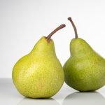 Bright and fresh green pears on a clean white background, symbolizing healthy eating and fresh produce.
